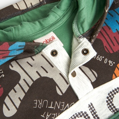 Peça de roupa com estampas coloridas, texto em inglês, interior verde e etiquetas visíveis.