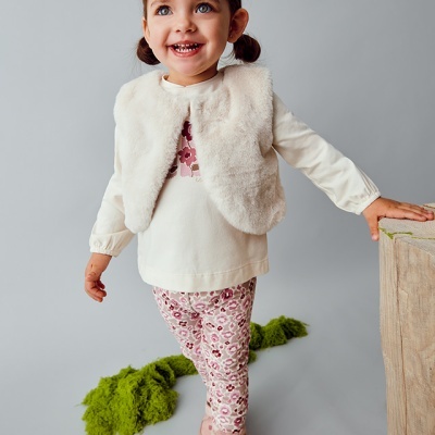 Menina a vestir roupas de criança em estúdio com fundo cinzento