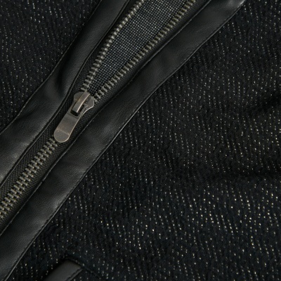 Fecho éclair metálico prateado numa peça preta com textura brilhante e acabamento em pele.