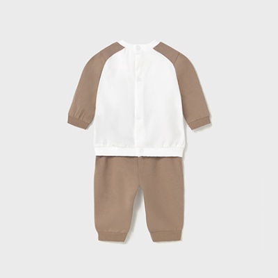 Conjunto bebé camisa branca e calças castanhas em fundo cinza