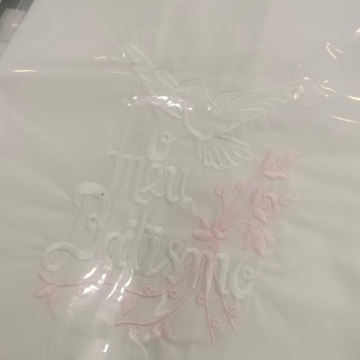 Tecido branco bordado com pomba e texto 'O Meu Batismo' em branco e rosa
