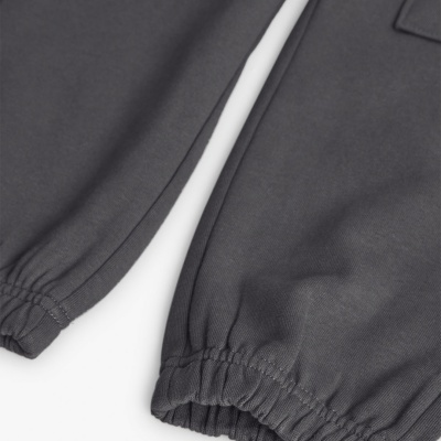 Detalhe da parte inferior de calças cinzentas com bainhas elásticas nos tornozelos