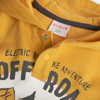 Roupa infantil amarela e branca com texto preto e botões de pressão amarelos.