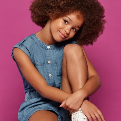 Jovem com vestido de ganga azul e ténis brancos sentada