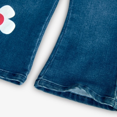 Calças de ganga azuis com aplicação de flor branca e vermelha