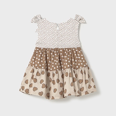 Vestido de criança com padrões de bolinhas e corações em tons castanhos e bege.