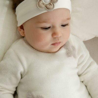 Bebé com camisola branca de flores e faixa de cabeça com flor