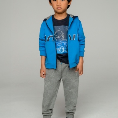 Menino vestido com casaco azul, t-shirt azul escura, calças cinza e ténis cinzentos