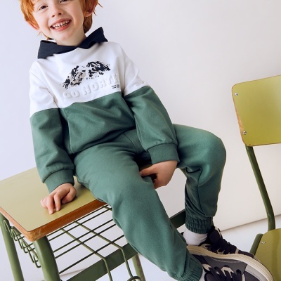 Criança com roupa desportiva e cadeiras escolares verdes