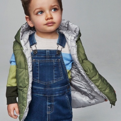 Criança com macacão de ganga, suéter às riscas e casaco acolchoado verde