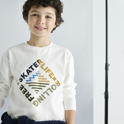 Camisola branca de criança com estampado e sweat azul amarrado na cintura.