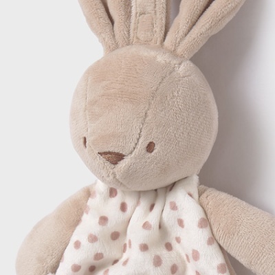 Pelúcia de coelho bege com roupa branca e pontos castanhos e etiqueta com texto