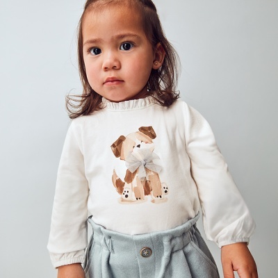 criança com camisola branca estampada e calças azul claro