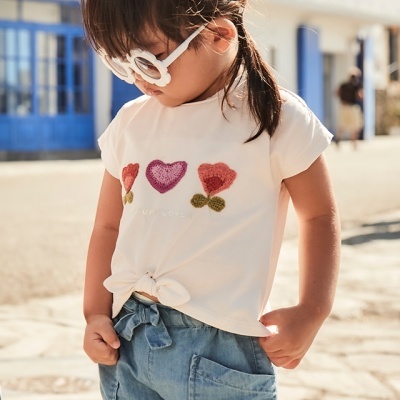 Menina com camisola branca de corações e calções de ganga azuis claros