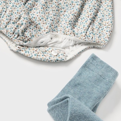 Conjunto de body de bebé manchado com leggings azuis.