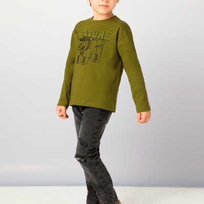 Camisola verde com texto, jeans pretos e ténis bege em criança