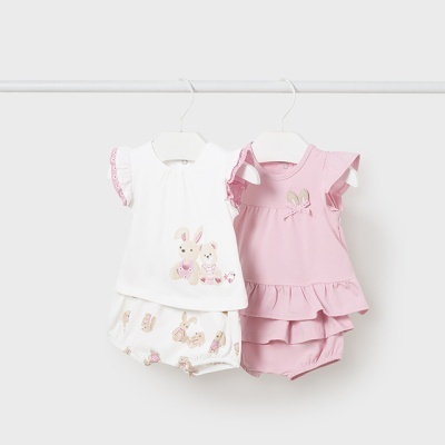 Dois conjuntos de roupa de bebé pendurados, um branco com coelhos e outro rosa com folhos.