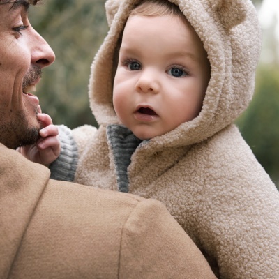 Bebé com casaco felpudo bege com orelhas no capuz ao ar livre