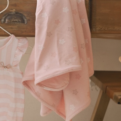 Manta cor-de-rosa com estrelas pendurada ao lado de vestido de riscas cor-de-rosa e branco