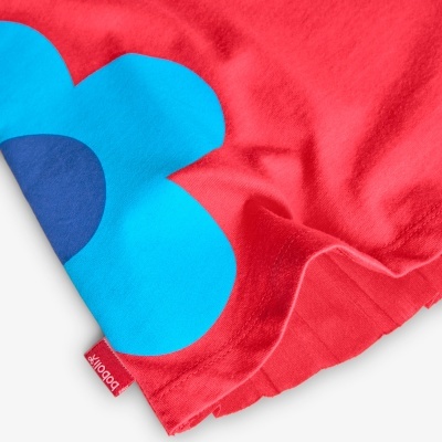 Detalhe de tecido vermelho com flor azul e etiqueta BOBO CHO