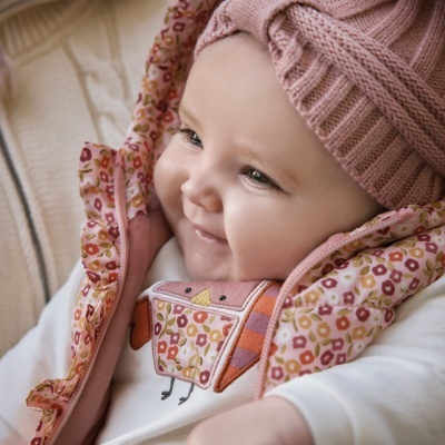 Bebé com roupa rosa e casaco floral sentado