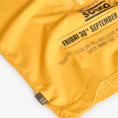 Detalhe de tecido amarelo com texto preto e etiqueta cinzenta 'NICE DAY'