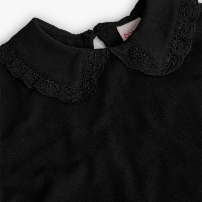 Parte superior de roupa preta com gola bordada e fecho atrás