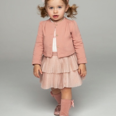 Menina pequena vestida com roupa rosa clara em fundo cinza