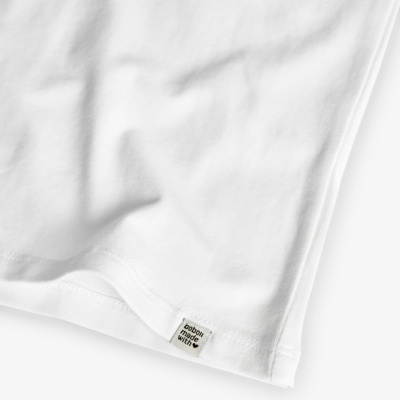Pormenor da bainha de uma t-shirt branca com etiqueta textil