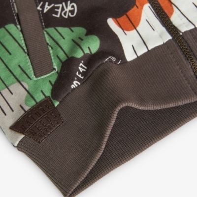 Detalhe da parte inferior de casaco castanho com estampado colorido e etiqueta de pele