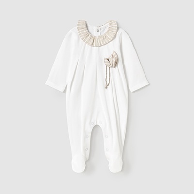 Macacão branco de bebé com gola e flor bege em fundo cinzento claro