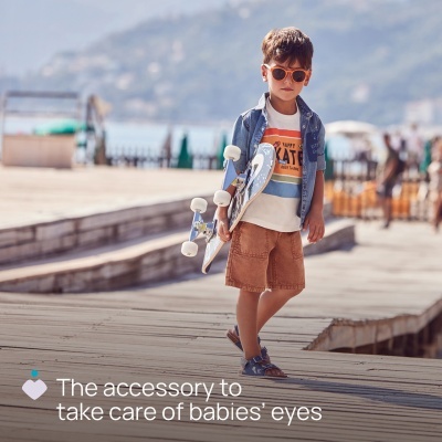 Menino com óculos de sol segurando skate num passeio de madeira