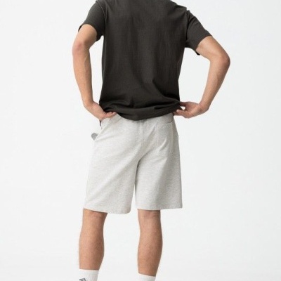 Homem com t-shirt preta, calções cinza claro, meias e sapatilhas brancas, visto de costas.