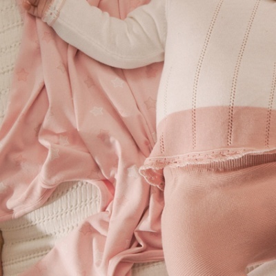 Manta rosa com estrelas e bebé vestido de rosa e branco