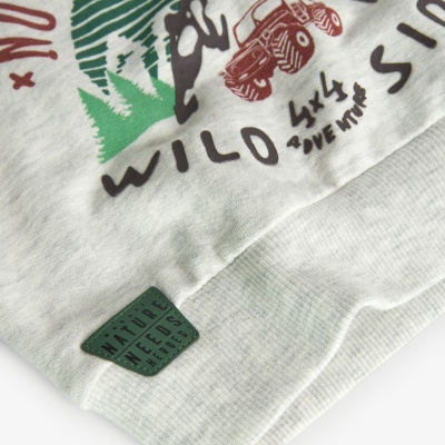 Detalhe de tecido com impressão e patch verde com texto.