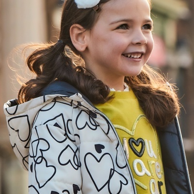 Rapazinha com casaco de corações e sweat amarela com bordado