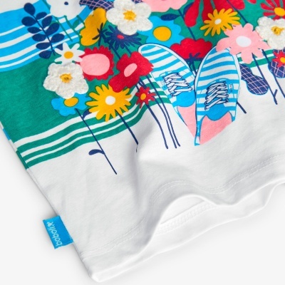 T-shirt branca com estampa colorida de flores e ténis azuis, etiqueta azul boboli