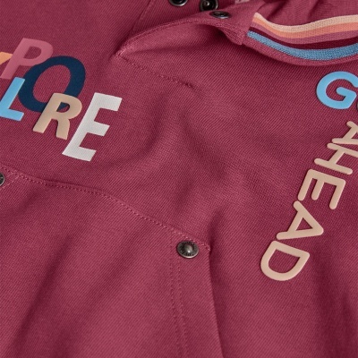 Peça de roupa vinho com texto colorido e fechos metálicos