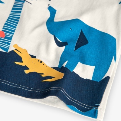 Detalhe de tecido branco com desenhos de elefante e crocodilo em azul e amarelo
