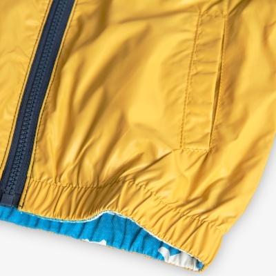 Peça de vestuário amarela com fecho azul e bainha elástica azul com padrão branco