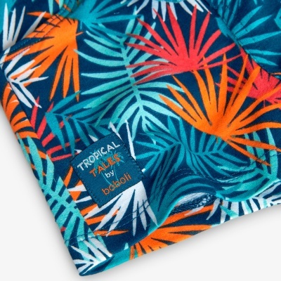 Tecido colorido com padrão de folhas e etiqueta TROPICAL TALES