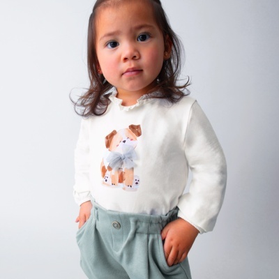 Criança com camisola branca estampada de cachorro e calções verdes