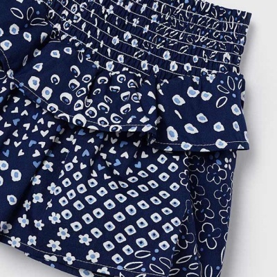 Calções azul escuro com padrões florais e geométricos brancos e claros, cintura franzida e volantes.