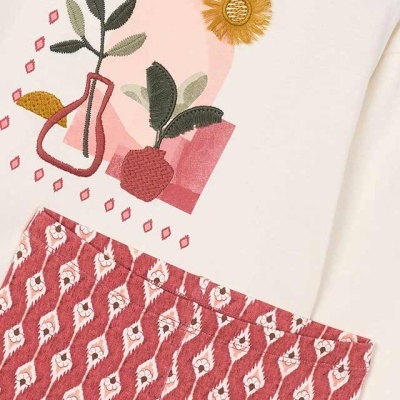 Conjunto de t-shirt branca com estampa floral e saia rosa com padrão geométrico.