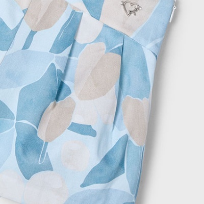 Saia curta de tecido com padrão floral azul, bege e branco e cinto com presilha metálica em forma de coração