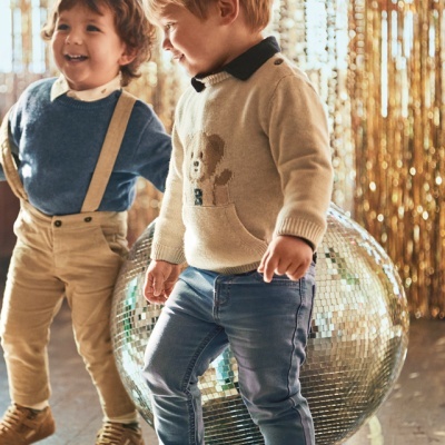Duas crianças vestidas para festa com cortinas douradas ao fundo.