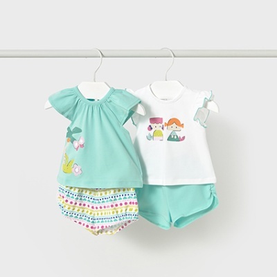 Dois conjuntos de roupa para bebé com t-shirts e calções em tons de azul e branco, pendurados em cabides