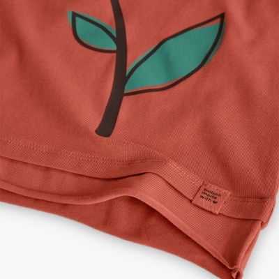 Detalhe de tecido terracota com estampa de planta e etiqueta organic cotton