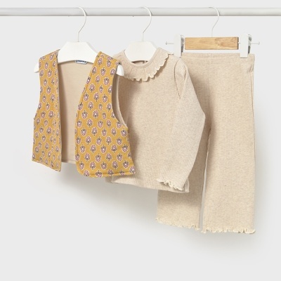 Conjunto infantil com colete amarelo estampado, camisola de malha bege e calças de malha bege pendurados em cabides.