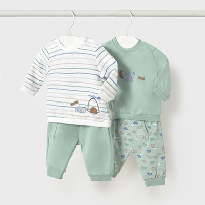 Conjuntos de roupa para bebé com camisolas e calças em tons verdes e padrões variados pendurados numa barra branca